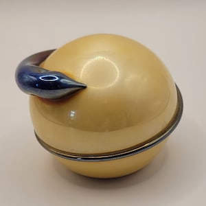 May include: A gold and blue round trinket box with a decorative handle. The box is made of metal and has a shiny finish.