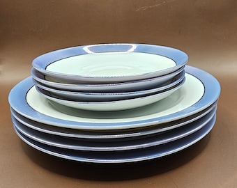 May include: A set of four blue and white ceramic plates with a decorative rim. The plates are stacked on top of each other.