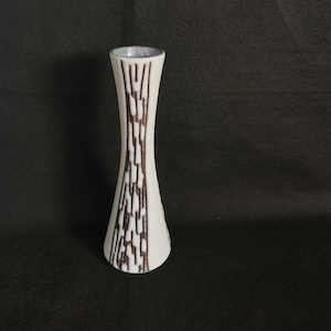 Könnte beinhalten: Eine weiße Keramikvase mit ausgestelltem Boden und schmalem Hals. Die Vase hat ein braunes, vertikales, strukturiertes Muster. Der Innenrand ist hellblau. Die Vase ist etwa 20 cm hoch.