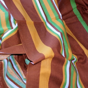 Può includere: Tessuto a righe in marrone, giallo, verde e bianco. Il tessuto è piegato e drappeggiato, mostrando il motivo.