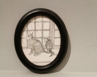 Peut inclure: Un dessin au crayon noir et blanc de deux chats regardant par une fenêtre. Le dessin est encadré dans un cadre ovale noir.