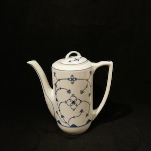 Op de afbeelding: Witte koffiekan van keramiek met een blauw-wit bloemenmotief. De kan heeft een deksel en een tuit.