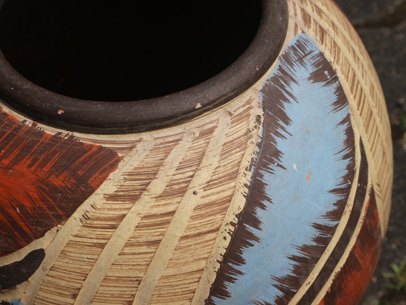 May include: A large, round, ceramic pot with a brown rim and a decorative design. The design features brown, white, and blue brushstrokes.