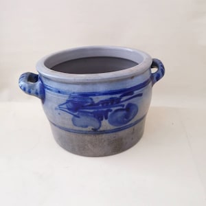 May include: A blue and white stoneware crock with two handles. The crock has a blue and white floral design.