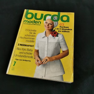 Puede incluir: Una revista vintage "Burda Moden" de julio de 1971, con una mujer con un atuendo blanco en la portada. La revista tiene un fondo amarillo y texto en alemán, incluyendo "Turban in 2 Stunden zu nähen."