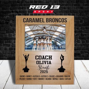May include: Wooden picture frame with a photo of a cheerleading team. The frame includes the text "CARAMEL BRONCOS", "COACH OLIVIA Stunt 2025", and a list of names. The top of the frame has the text "RED 13 SPORT".