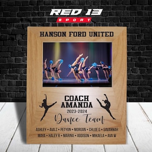 May include: A wooden photo frame with a picture of a dance team in the center. The frame has the text "RED 13 SPORT" at the top, "HANSON FORD UNITED" below that, and "COACH AMANDA 2023-2024 Dance Team" at the bottom. The names of the dancers are listed below the text.