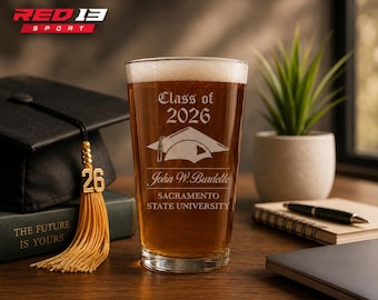 May include: A pint glass filled with beer, engraved with "Class of 2026," a graduation cap, and the name "John W. Burdette" from Sacramento State University. A graduation tassel and mortarboard are visible in the background.