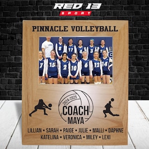 May include: A wooden picture frame with a photo of a girls' volleyball team. The frame has the text "Pinnacle Volleyball" and "Coach Maya" with a volleyball graphic. The names of the players are listed below the photo.