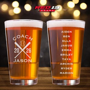 May include: Two clear pint glasses filled with beer, featuring white foam. One glass has "COACH 2026 JASON" with baseball bats and ball. The other glass lists names. The logo "RED 13 SPORT" is at the top.