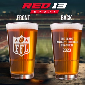May include: A clear glass beer stein with a white design on the front that says "FFL" with two stars and a football. The back of the stein says "The Bears Fantasy Football Champion 2023".