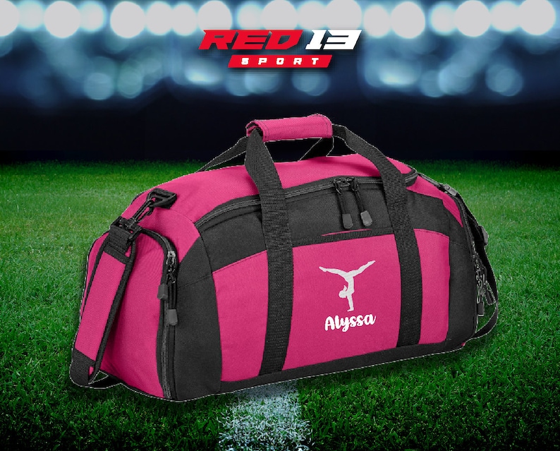 May include: Pink and black duffel bag with a white gymnast silhouette and the name "Alyssa" embroidered on the front. RED13 SPORT is printed on the bag.