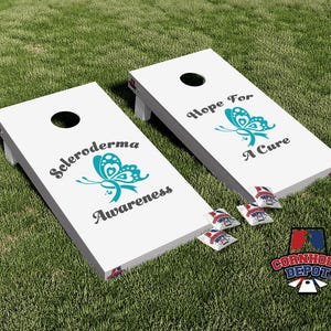 May include: Two white cornhole boards with black holes and teal butterfly graphics. One board reads "Scleroderma Awareness" and the other says "Hope For A Cure." Includes bean bags and a "Cornhole Depot" logo.