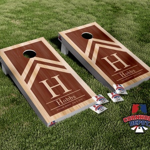 May include: Two personalized cornhole boards with a brown and beige chevron design. The boards feature the letter "H" and the name "Hobbs" with the text "Established June 8, 2024".