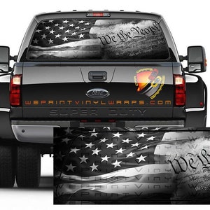 May include: A black pickup truck with a rear window decal featuring a black and white American flag with the words "We the People" and the preamble to the US Constitution. The truck has a "Super Duty" emblem on the tailgate.