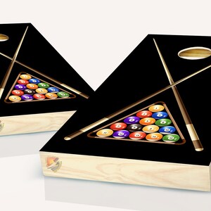 May include: Two black wooden cornhole boards with a pool table design. Each board features a triangle of billiard balls and two crossed pool cues.