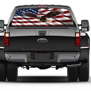 May include: A black pickup truck with a rear window decal of an American flag with a bald eagle flying over it. The truck says "Super Duty" on the tailgate.