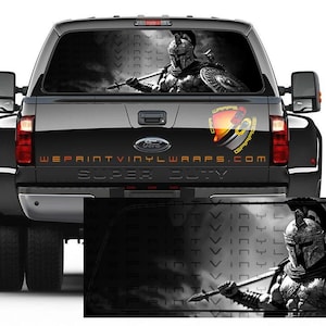 May include: Black Ford Super Duty truck with a rear window graphic featuring a Spartan warrior holding a spear and shield. The graphic is in grayscale. The text "WEPRINTVINYLWRAPS.COM" is visible on the tailgate.