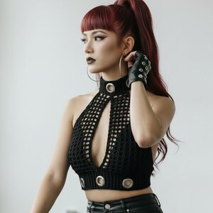May include: Black crochet halter top with a keyhole design and silver grommet details. The top is paired with black leather pants and fingerless gloves. The model has red hair and large hoop earrings.