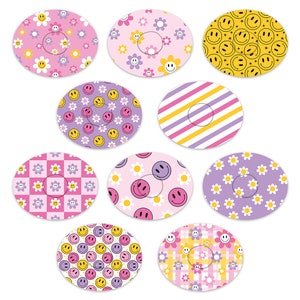Puede incluir: Diez pegatinas redondas con diferentes patrones. Los patrones incluyen caritas sonrientes amarillas, flores rosas y moradas, rayas rosas y amarillas y patrones de cuadros rosas y amarillos.
