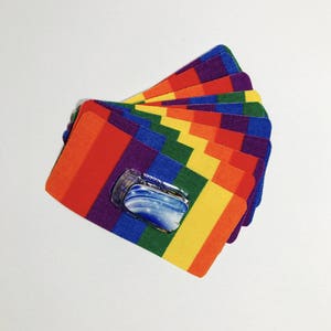 Peut inclure: Un empilement de patchs en tissu aux couleurs de l'arc-en-ciel avec un petit autocollant transparent bleu et blanc sur le patch du dessus.