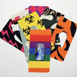 Peut inclure: Assortiment de pansements adh&eacute;sifs &agrave; motifs color&eacute;s avec un motif arc-en-ciel au centre. Les pansements pr&eacute;sentent une vari&eacute;t&eacute; de motifs, notamment des symboles de danger biologique, du camouflage et des rayures.