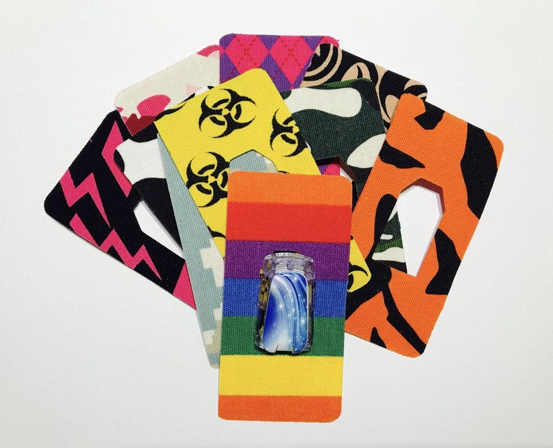 Peut inclure: Assortiment de pansements adh&eacute;sifs &agrave; motifs color&eacute;s avec un motif arc-en-ciel au centre. Les pansements pr&eacute;sentent une vari&eacute;t&eacute; de motifs, notamment des symboles de danger biologique, du camouflage et des rayures.