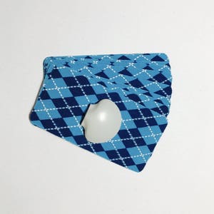Op de afbeelding: Een kaartspel met een blauw-wit geruit patroon. De kaarten zijn gewaaid en een wit hartvormig object is bovenop het spel gelegd.