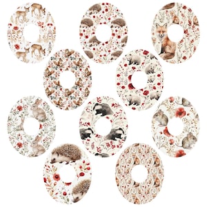 May include: Ten round stickers with a white background and a ring in the centre. Each sticker features a different woodland animal, including a fox, a badger, a hedgehog, a squirrel, a rabbit, and a mouse. The animals are surrounded by red flowers and green leaves.