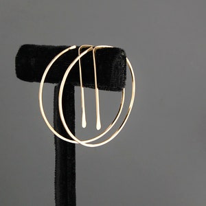 Peut inclure: Une paire de boucles d'oreilles cr&eacute;oles en or avec un cercle plus petit &agrave; l'int&eacute;rieur du cercle plus grand. Les boucles d'oreilles sont sur un pr&eacute;sentoir en velours noir.