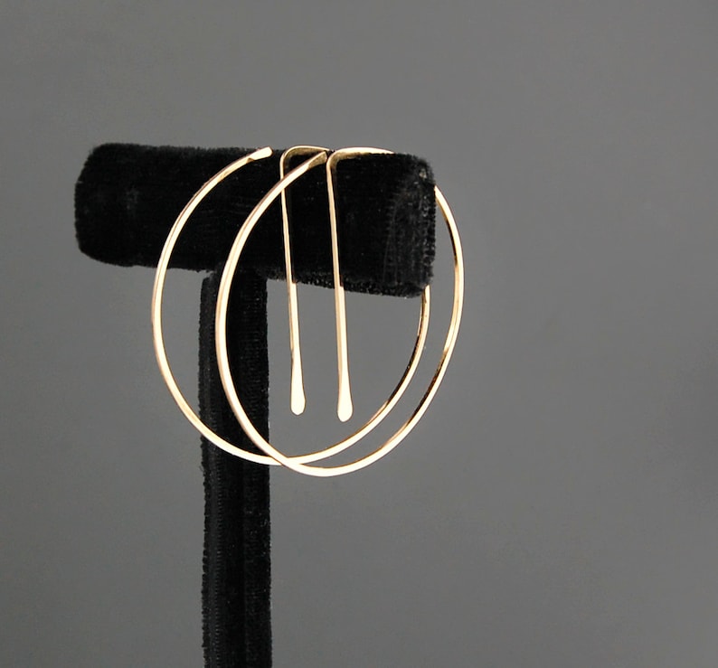 Peut inclure: Une paire de boucles d'oreilles cr&eacute;oles en or avec un cercle plus petit &agrave; l'int&eacute;rieur du cercle plus grand. Les boucles d'oreilles sont sur un pr&eacute;sentoir en velours noir.