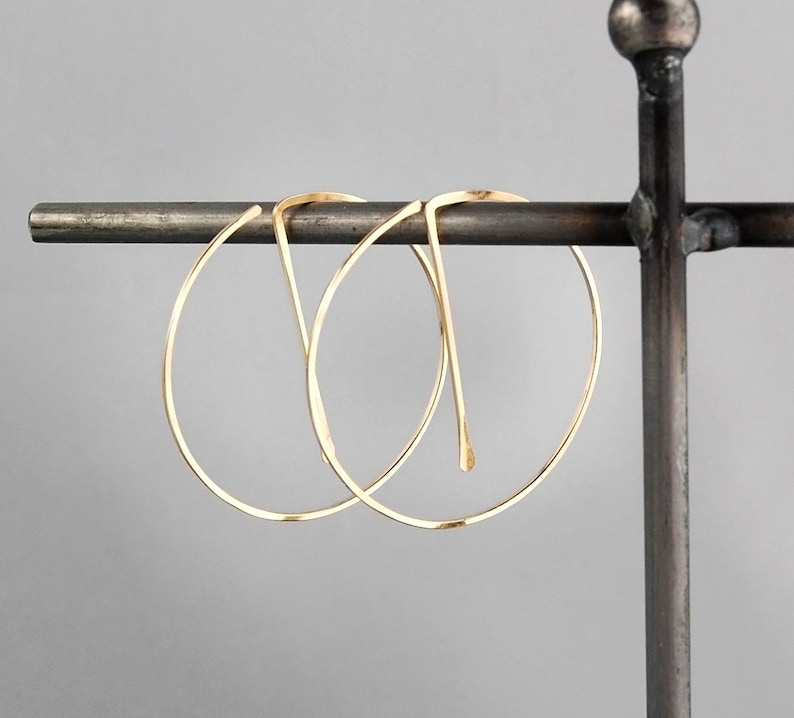 Peut inclure: Deux cr&eacute;oles en or suspendues &agrave; un support en m&eacute;tal. Les cr&eacute;oles sont simples et &eacute;l&eacute;gantes, avec une finition lisse et polie.