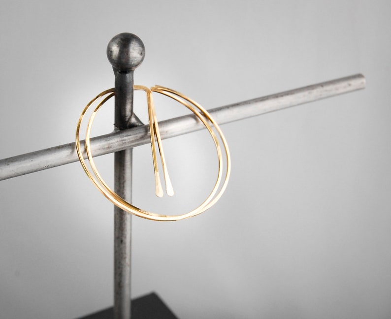 Peut inclure: Boucles d'oreilles cr&eacute;oles en or avec un design &agrave; double cercle. Les boucles d'oreilles sont pr&eacute;sent&eacute;es sur un support en m&eacute;tal.