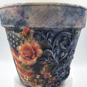 Whimsical terracotta pot. Patriotic flag and rose decoupage design, floral scroll clay relief. Texture and distressed finish for aged look.