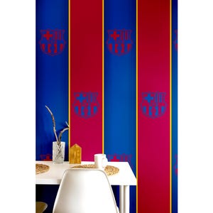 Può includere: Carta da parati con un motivo ripetuto di strisce verticali blu e rosse con lo stemma del FC Barcelona. Lo stemma è rosso e blu. Un tavolo bianco con un vaso, una casa decorativa e una tazza è di fronte alla carta da parati.