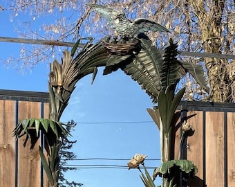 May include: A large, ornate mirror with a gold and green finish. The mirror is framed by a sculpted design of palm leaves, birds, and flowers. The mirror is mounted on a wooden base with a carved dragon design.
