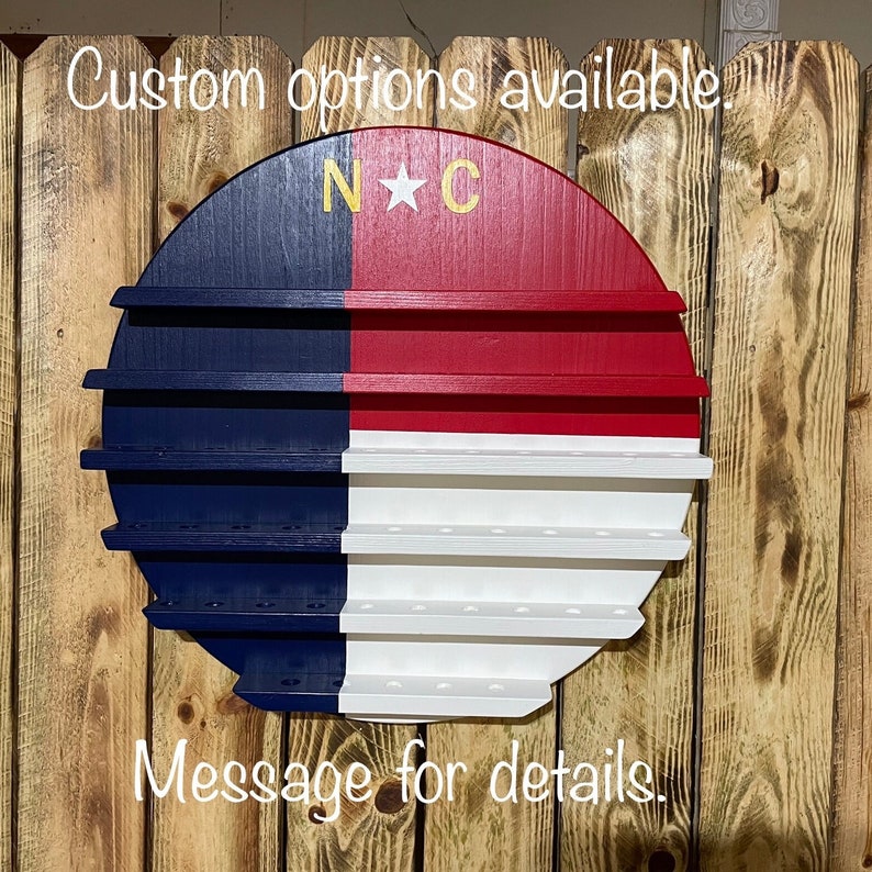 May include: A round wooden shelf painted in the colors of the North Carolina flag. The shelf has multiple tiers and is decorated with a gold star and the letters "N*C".