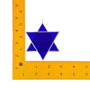 May include: A blue stained glass Star of David ornament with silver lead cames. The ornament is approximately 4 inches in diameter.