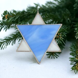 May include: A blue and white stained glass Star of David ornament. The star is made of glass and has a silver frame.