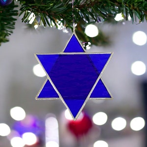 May include: A blue glass Star of David ornament hanging from a Christmas tree.