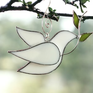 May include: White stained glass dove with a green olive branch, hanging from a branch.