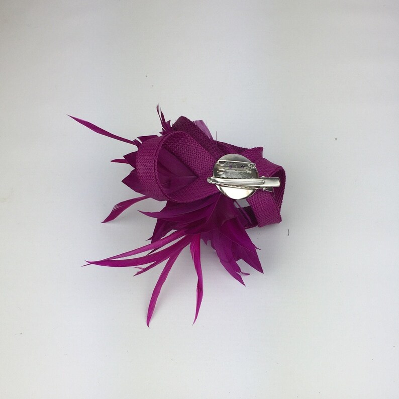 May include: A magenta feather and ribbon flower hair clip with a silver clasp.