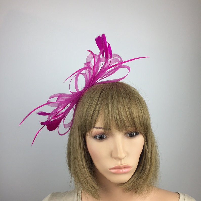 May include: A fuchsia pink feather and tulle hair comb. The comb is decorated with a large bow made of tulle and feathers.