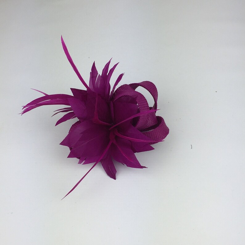 May include: A magenta feather flower hair clip with a magenta ribbon.