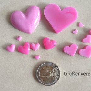 Puede incluir: Comparaci&oacute;n de tama&ntilde;os de piezas de resina en forma de coraz&oacute;n rosa. El coraz&oacute;n m&aacute;s grande es aproximadamente del tama&ntilde;o de una moneda de 2 euros. Los corazones m&aacute;s peque&ntilde;os var&iacute;an en tama&ntilde;o desde unos pocos mil&iacute;metros hasta aproximadamente 1 cent&iacute;metro.