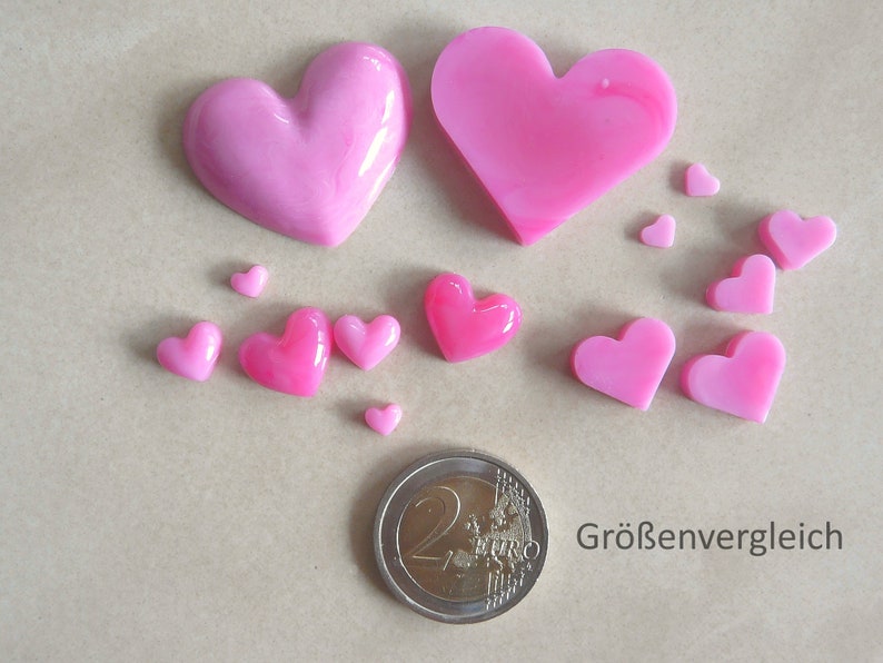 Puede incluir: Comparaci&oacute;n de tama&ntilde;os de piezas de resina en forma de coraz&oacute;n rosa. El coraz&oacute;n m&aacute;s grande es aproximadamente del tama&ntilde;o de una moneda de 2 euros. Los corazones m&aacute;s peque&ntilde;os var&iacute;an en tama&ntilde;o desde unos pocos mil&iacute;metros hasta aproximadamente 1 cent&iacute;metro.