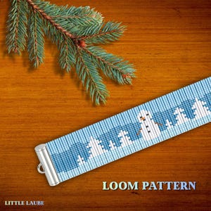 May include: A blue and white loom pattern featuring a winter scene with snowmen and trees. The pattern has a silver clasp and the text "LOOM PATTERN" and "LITTLE LAUBE". A sprig of evergreen is in the background.