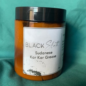 Pu&ograve; includere: Un barattolo di vetro marrone con un coperchio nero e un'etichetta bianca che recita "BLACK Sloth Sudanese Kar Kar Grease".