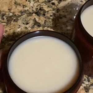 Pu&ograve; includere: Due barattoli marroni pieni di una crema beige chiaro. I barattoli sono su un piano di lavoro macchiato.