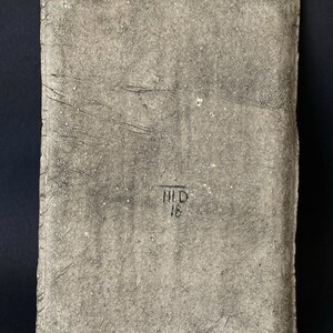Pu&ograve; includere: Una piastrella di ceramica rettangolare, testurizzata e di colore grigio con il testo "HID 18" stampato in nero.